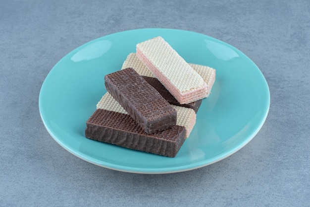 Chocolate and caramel wafers on green plate over grey.