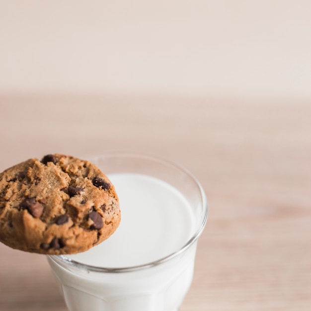 무료 사진 우유와 함께 유리 가장자리에 초콜릿 칩 쿠키 균형