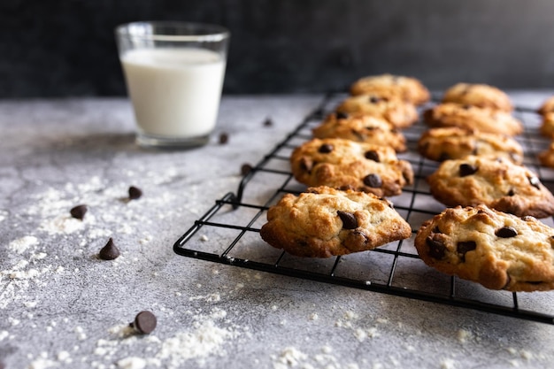 Biscotti con gocce di cioccolato su una griglia a raffreddare con un bicchiere di latte