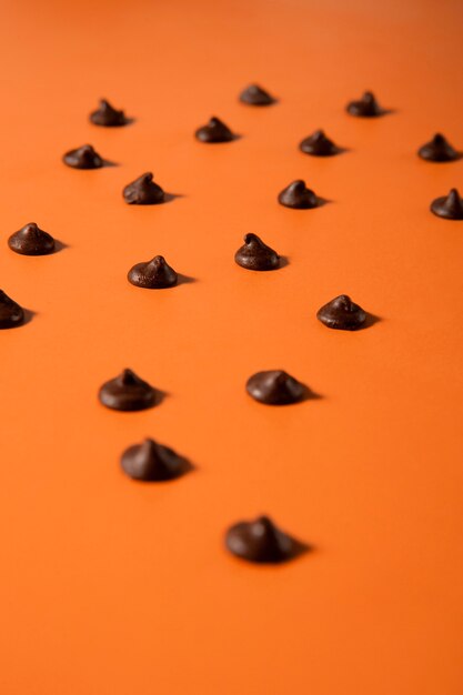 Foto gratuita assortimento di gocce di cioccolato con sfondo arancione