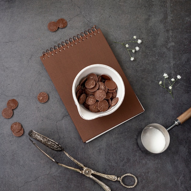 Chocolate chips on a brown notebook on a grey background