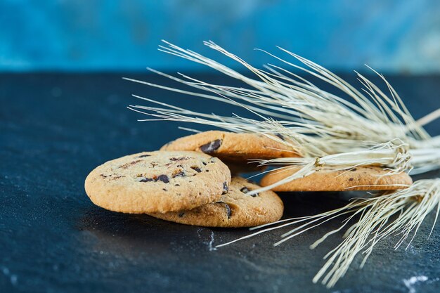 Chocolate chips cookies on a marble surface with ears of wheat