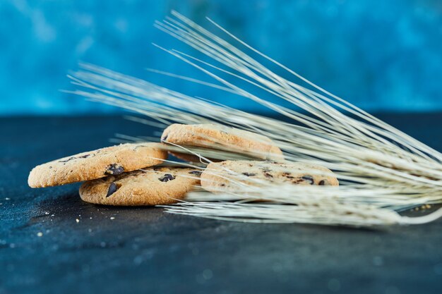 Chocolate chips cookies on a marble surface with ears of wheat