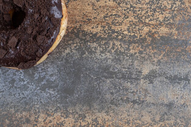 Chocolate coated donut displayed on marble surface