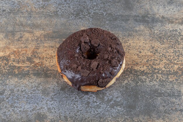 Chocolate coated donut displayed on marble surface