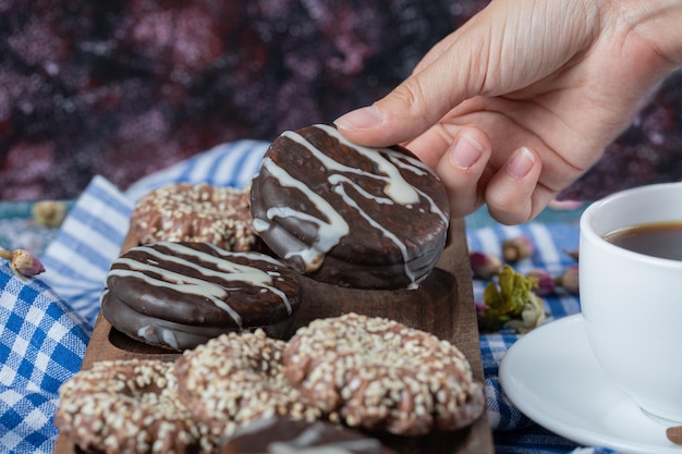 Free photo chocolate and coconut cookies on wooden board served with a cup of tea.