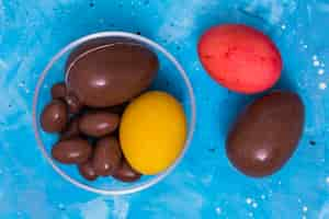 Free photo chocolate and colorful easter eggs on blue table