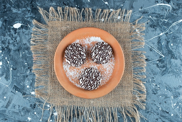 Chocolate cookie on clay plate on texture on blue. 