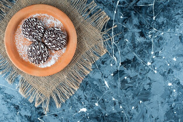 Chocolate cookie on clay plate on texture on blue. 