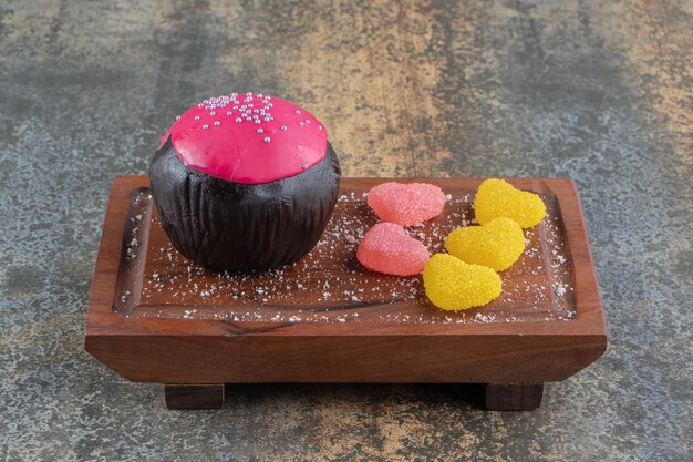 Foto gratuita biscotto al cioccolato con glassa rosa e caramelle su tavola di legno