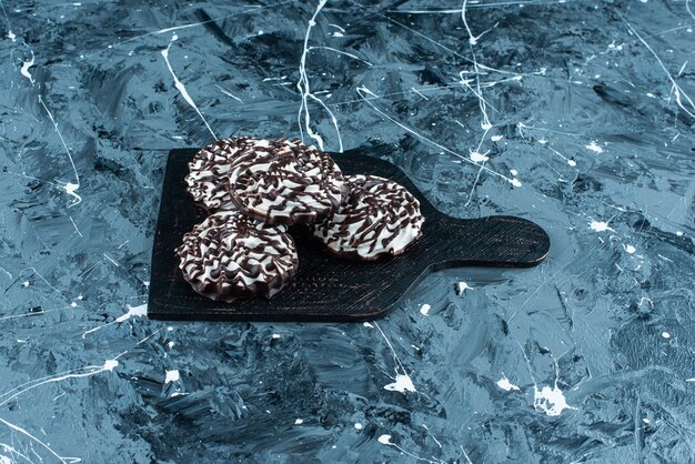 Chocolate cookies on a cutting board, on the blue table. 