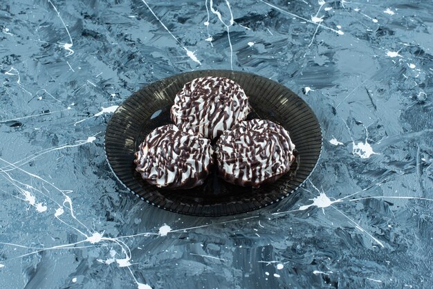 Chocolate cookies on glass plate on blue. 