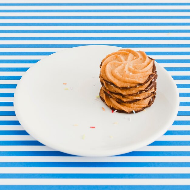 青と白の縞背景の上にプレート上のチョコレートクッキー