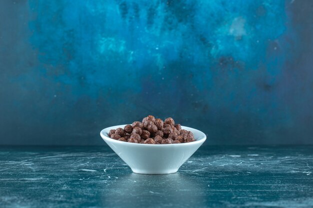 青い背景に、ボウルにチョコレートコーンボール。高品質の写真