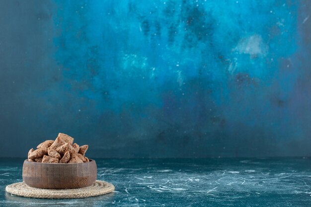 青い背景の上のtrivet 、、のボウルにチョコレートコーンパッド。高品質の写真