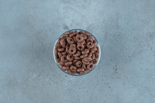 Foto gratuita anello di mais al cioccolato in un piedistallo di vetro, sullo sfondo blu.