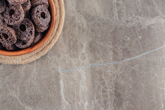 Chocolate corn rings in a bowl on trivet on blue.