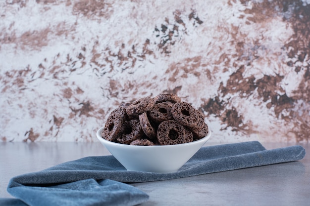 Foto gratuita anelli di mais al cioccolato isolati su piastra bianca su una superficie di pietra