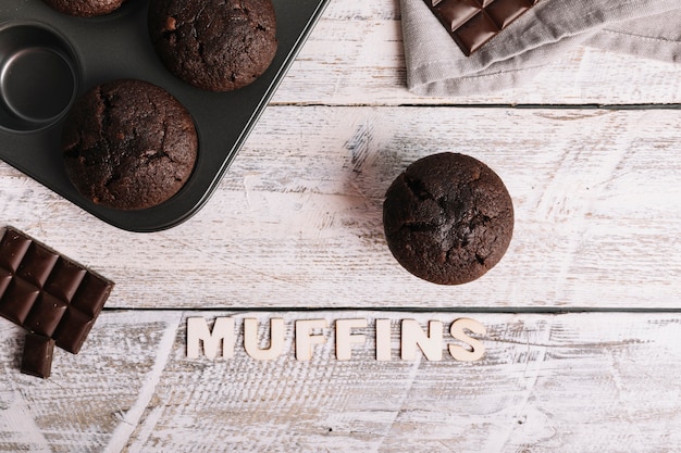 Chocolate cupcake on white wooden table with muffin text