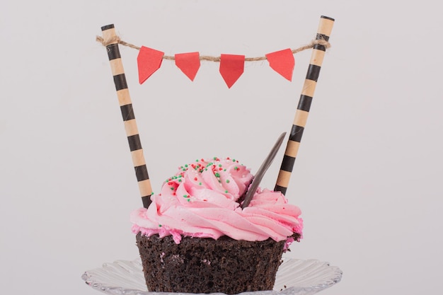 Chocolate cupcake with frosting and sprinklers on glass.