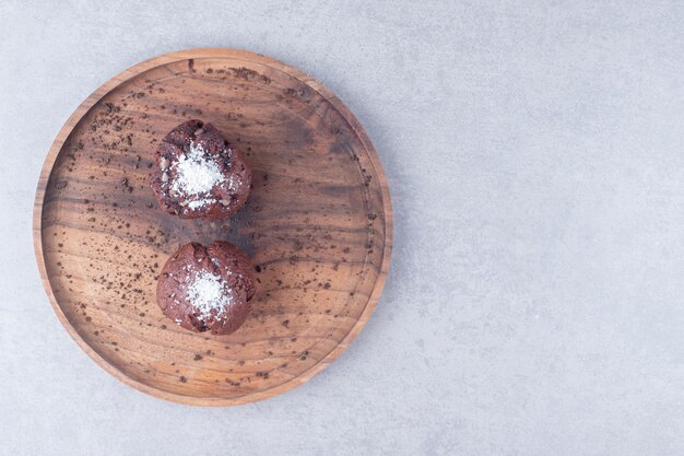 Chocolate cupcakes on a wooden tray on marble