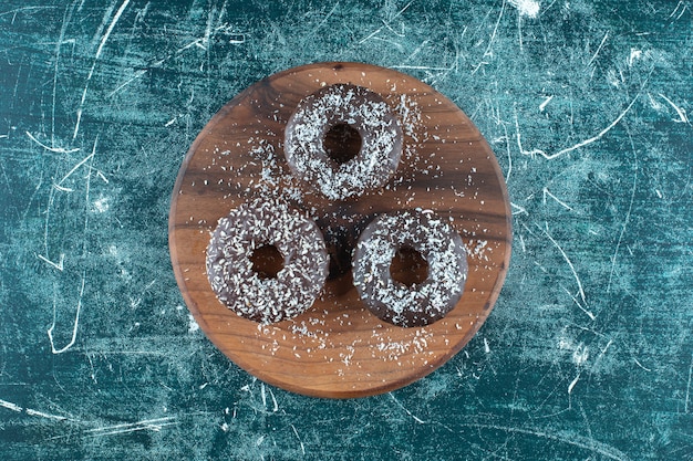 Chocolate donuts on the board , on the blue background. High quality photo