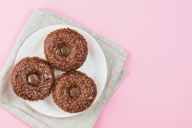 Chocolate donuts on plate on gray material