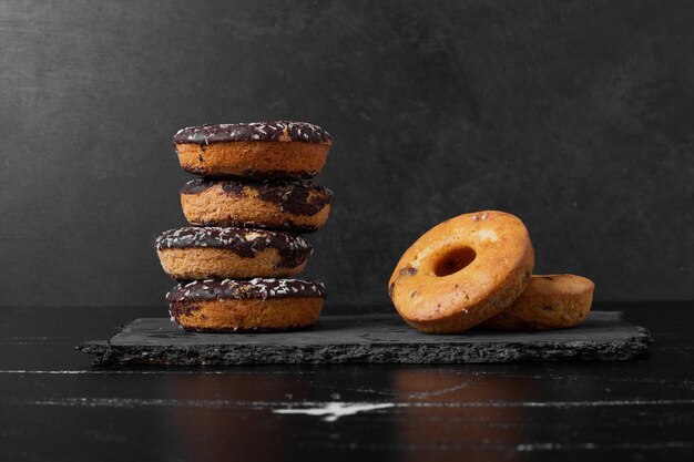 Chocolate doughnuts on a stone platter.