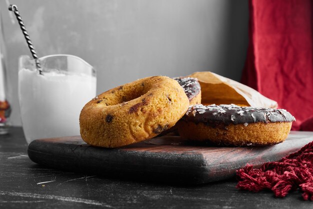 Chocolate doughnuts on a wooden board with curd. 