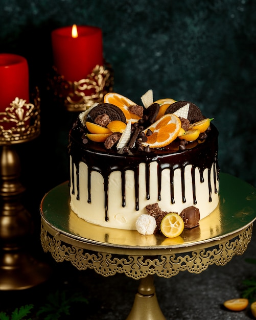 Chocolate drip cake garnished with orange chocolate cookies and waffles