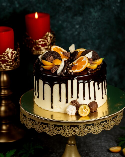 Chocolate drip cake garnished with orange chocolate cookies and waffles