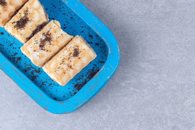 Chocolate filled waffle rolls in a blue platter on marble