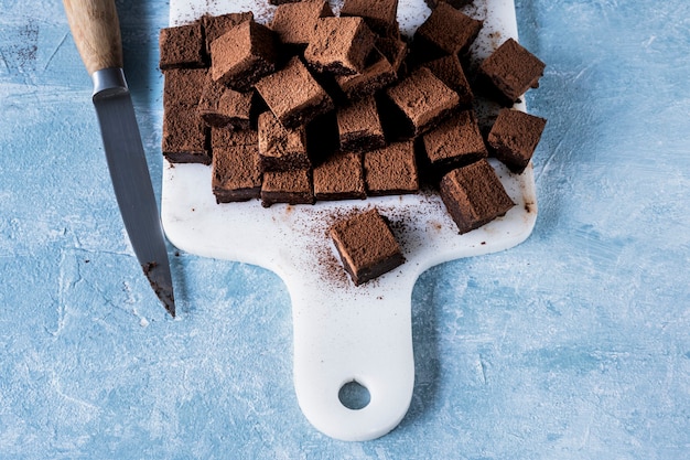 Chocolate ganache truffle squares dusted with cacao being cut into cubes