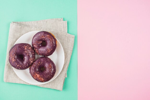 핑크와 민트 배경에 접시에 초콜릿 글레이즈 도넛