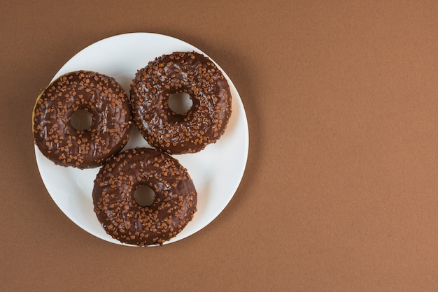 Chocolate glazed doughnuts on white plate