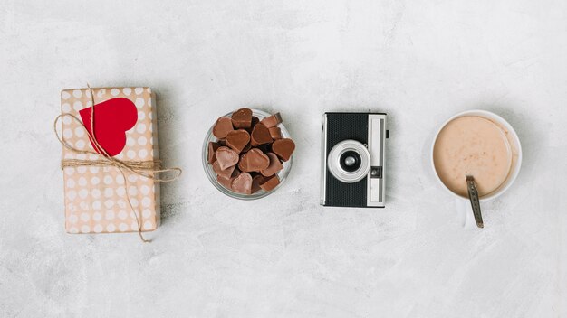 Chocolate hearts, present box, camera and cup of drink 