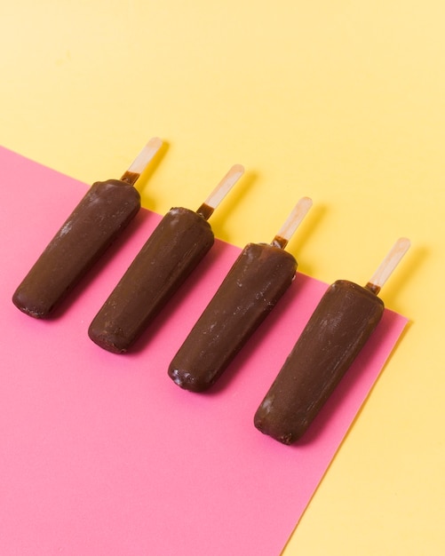 Chocolate ice cream on stick aligned on table