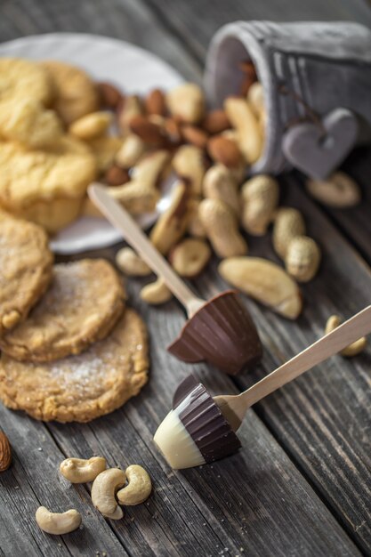 小さなカップの形をしたチョコレートロリーと木のバケツにさまざまなナッツ