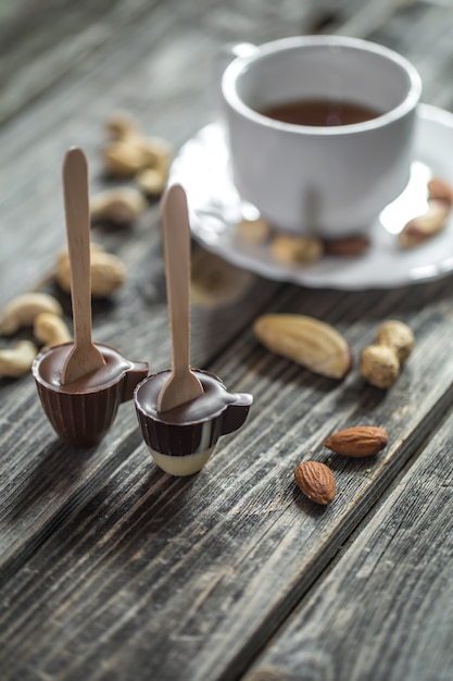 chocolate Lolly in the shape of a small Cup with a Cup of tea and nuts on wood