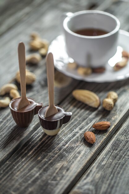 шоколадка на палочке в виде маленькой чашки с чашкой чая и орехами по дереву
