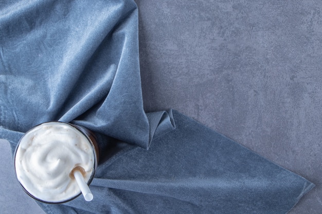 Chocolate mocha in a glass on piece of fabric, on the blue table.