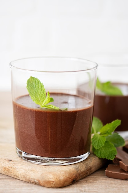 Chocolate mousse dessert garnished with mint leaf on wooden table and white background