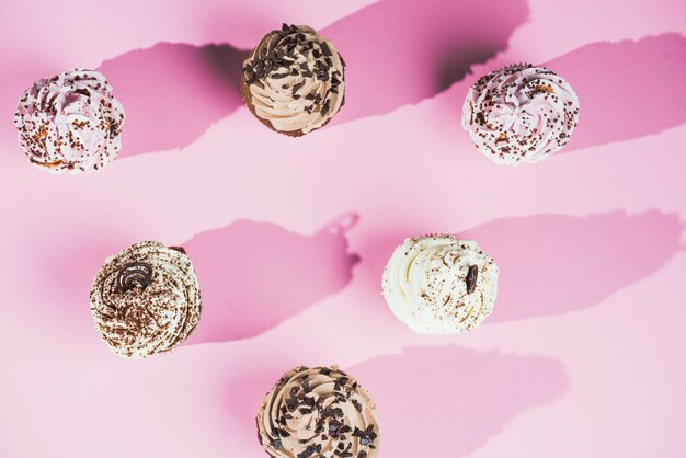Chocolate muffins filled with sweet cream over pink background