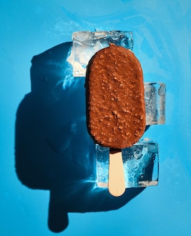 파란색 배경에 얼음 조각에 초콜릿 너트 아이스크림. 햇빛. 여름 개념입니다.