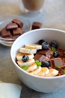 그릇에 블루베리, 민트 잎, 바나나를 넣은 초콜릿 오트밀 죽. 아침 식사 개념