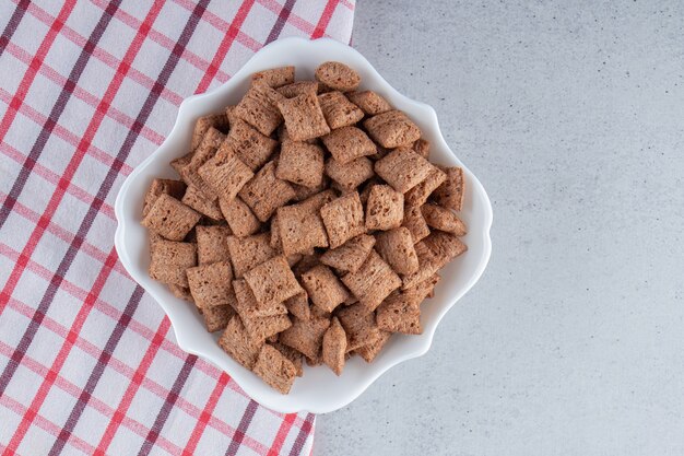 Free photo chocolate pads cornflakes in white bowl on stone background. high quality photo