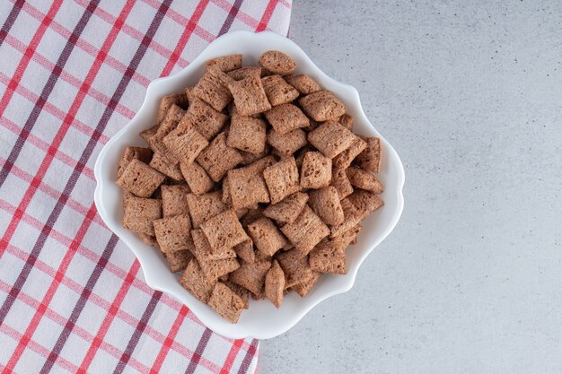 Chocolate pads cornflakes in white bowl on stone background. High quality photo