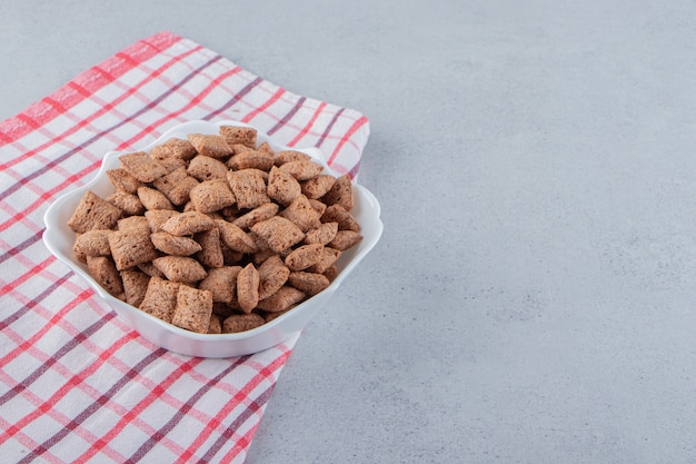 Free photo chocolate pads cornflakes in white bowl on stone surface