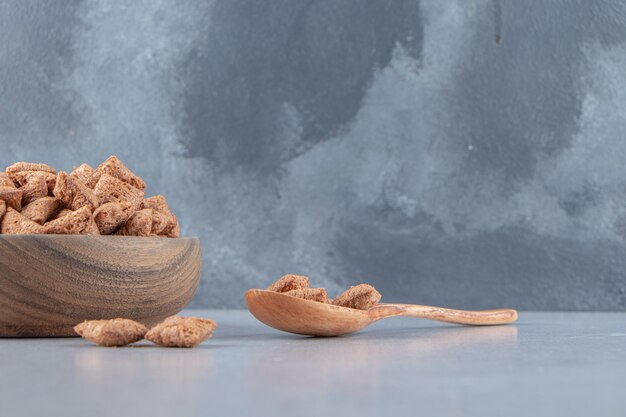 Chocolate pads cornflakes in wooden bowl on stone background. High quality photo