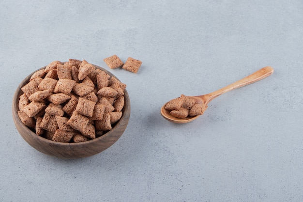 Chocolate pads cornflakes in wooden bowl on stone background. High quality photo